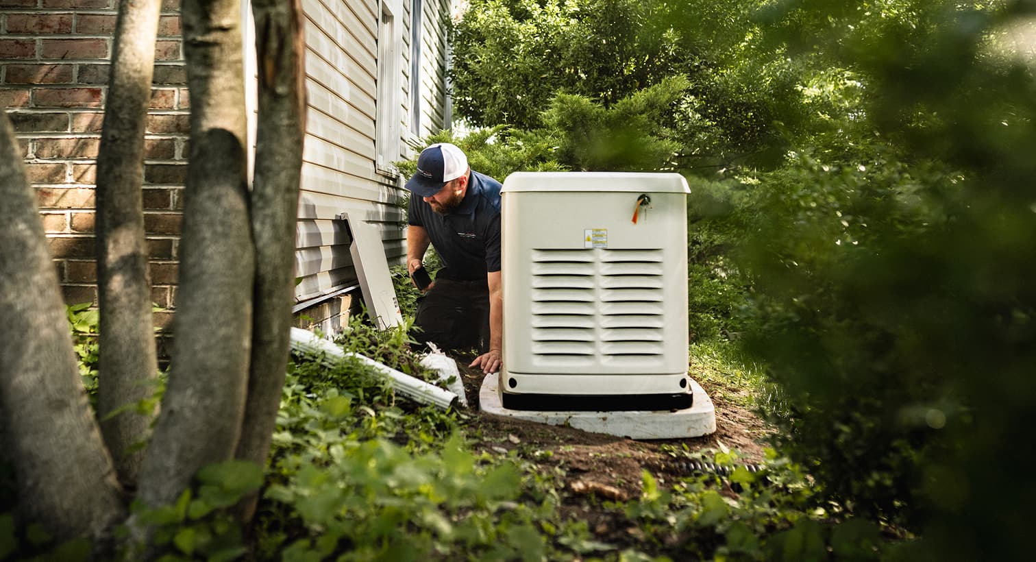 A professional Fenwick Waychoff's technician inspects a large, beige whole-home standby generator installed on a concrete pad outside a residential house.