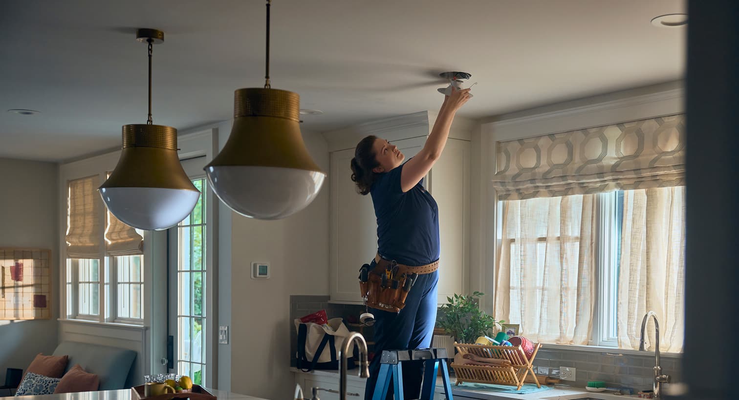 A professional Fenwick Waychoff's electrician standing on a ladder to install modern recessed ceiling lights during a residential electrical installation service.
